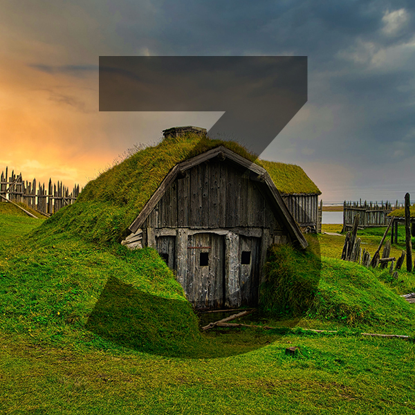 A Hobbit style house with a thatched roof and a fence in the background