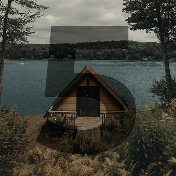A small A frame cabin on a lake in the wilderness